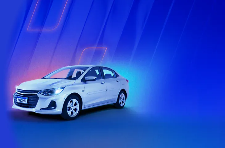 Na imagem, temos um carro sedan branco com faróis acesos. Ao fundo, temos luzes rosa e azul claro em um fundo azul marinho.