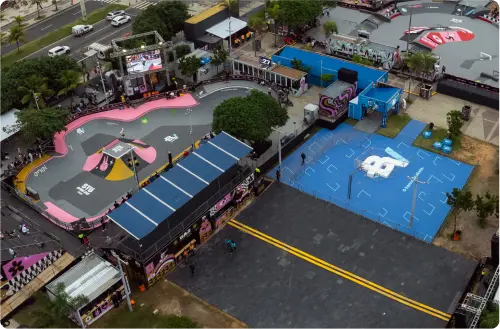 No canto esquerdo, uma pista de skate pintada de cinza, rosa e amarelo e tem o logo do banco BV.