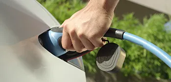 Homem utilizando carregador elétrico em automóvel.