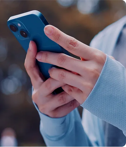 Uma pessoa mexendo no celular com as duas mãos.