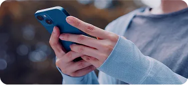 Uma pessoa mexendo no celular com as duas mãos.