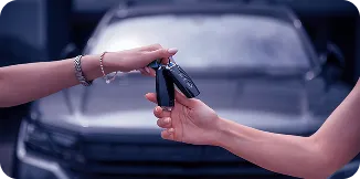 Uma pessoa passando a chave de um carro para outra com o carro ao fundo.