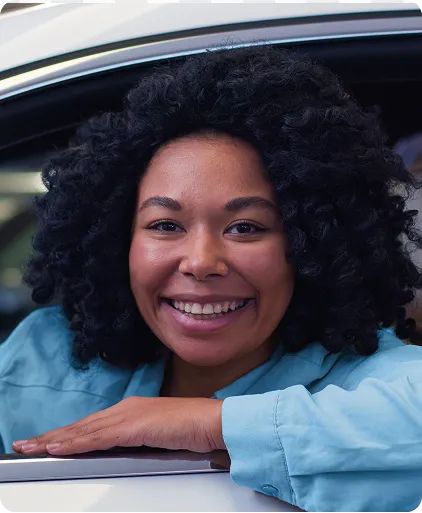 Mulher sorrindo dentro de um carro enquanto apoia na janela dele.