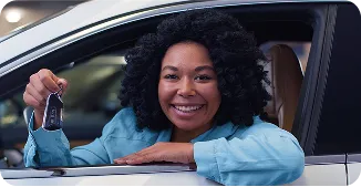 Mulher sorrindo dentro de um carro enquanto apoia na janela dele.