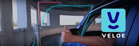 Uma pessoa dentro de um carro, que usa a Tag Veloe do banco BV, dando joia para um sistema de cobrança no estacionamento.