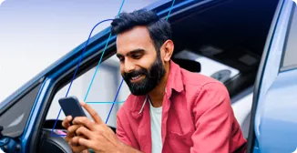 Homem de camisa vermelha sentado dentro do carro utilizando o celular