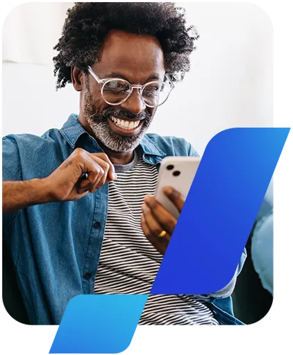 Um homem negro, de barba grisalha e óculos, olha feliz para o celular.