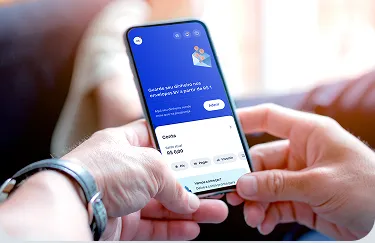 Pessoa segurando o celular com app do BV na tela de conta digital.