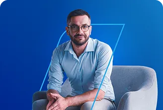 Na imagem, temos um homem sentado em uma poltrona azul clara