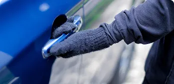 Mão de luva abrindo a maçaneta do carro.