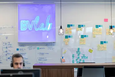 Um quadro branco tem o logo BVLab e post its amarelos e azuis.