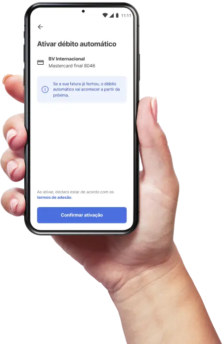 Mão segurando um celular, com o aplicativo do BV aberto na opção de ativar o débito automático e os dados do cartão visíveis.