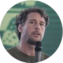 Ex-judoca Flávio Canto, de camiseta verde e falando em um microfone.