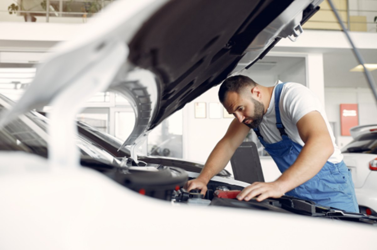 Mecânico conferindo carro em garagem veicular.