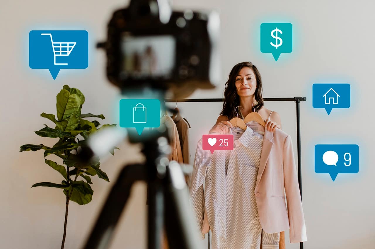 Influencer de social commerce fazendo live stream para vender roupas. Ela usa uma câmera no tripé para transmitir a live.